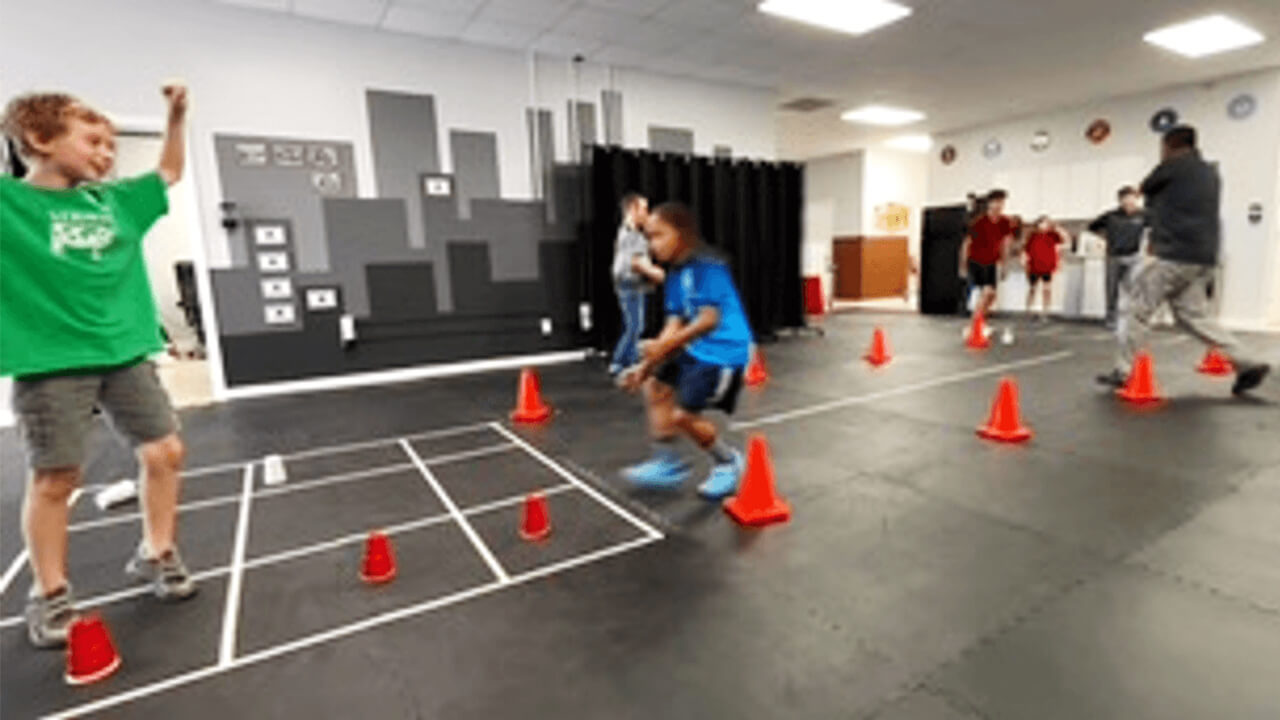 Children run and jump around cones during a training session.
